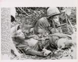 Aid and Protection: pistol drawn and his body protecting that of wounded U.S. paratrooper, medic PFC Andrew G. Brown of Chicago searches jungle for sniper. He and Spec. 4 Gerald Levy of New York crawled through the jungle to dress the wounds of the unidentified paratrooper while a live grenade, ready to go ff at the slightest movement, lay nearby. Action took place yesterday near Thuong Lang, Vietnam