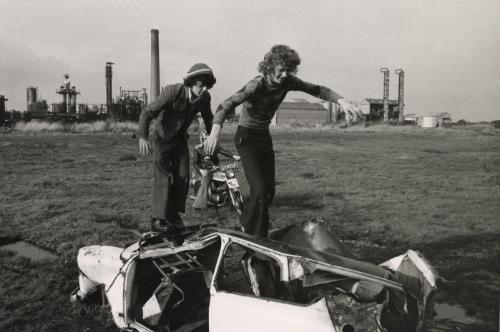 Boy balancing on abandoned car, Manchester, England