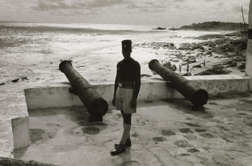 Soldier wearing fez hat in front of water, Ghana