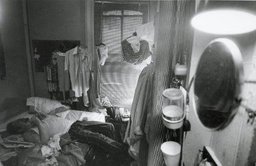 Man lying on bed in cluttered room, NYC