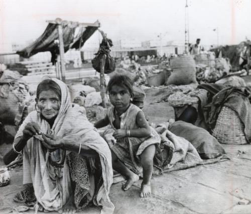 Women's Lot is Poverty: an Indian woman rests in her "home," in squatter area of Bombay. A girl plays nearby. Other families live in similar shocking poverty. Indian women have followed their husbands from the drought stricken rural homes to the cities where they had hope of finding food and shelter