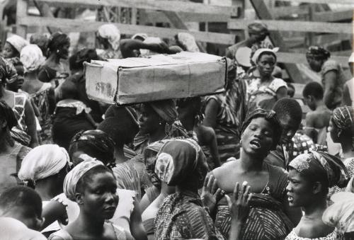 Street scene with woman talking an a woman balancing a box on her head, Ghana
