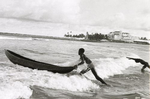 Man pushing boat into the ocean, Ghana