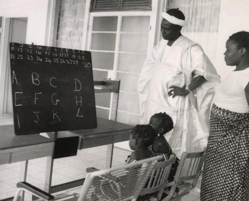 Family at home teaching their children the alphabet, likely Dakar, Senegal, Africa