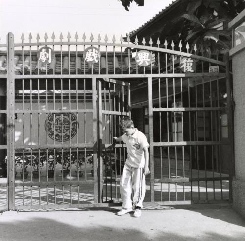 American boy closing gate at martial arts school, Taiwan